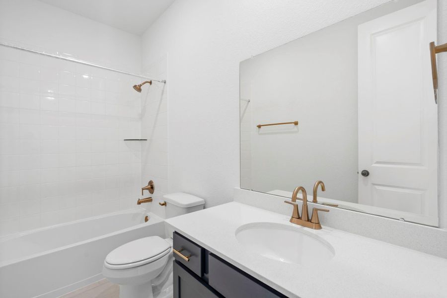 The secondary bath features tile flooring, dark stained cabinetry and light countertops and a shower/tub combo. Perfect for accommodating any visiting family and friends.