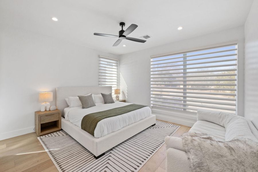 Bedroom with light wood finished floors, ceiling fan, and recessed lighting