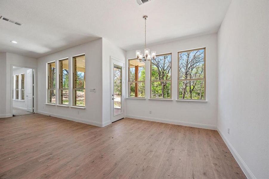 Spare room with an inviting chandelier and light wood-type flooring