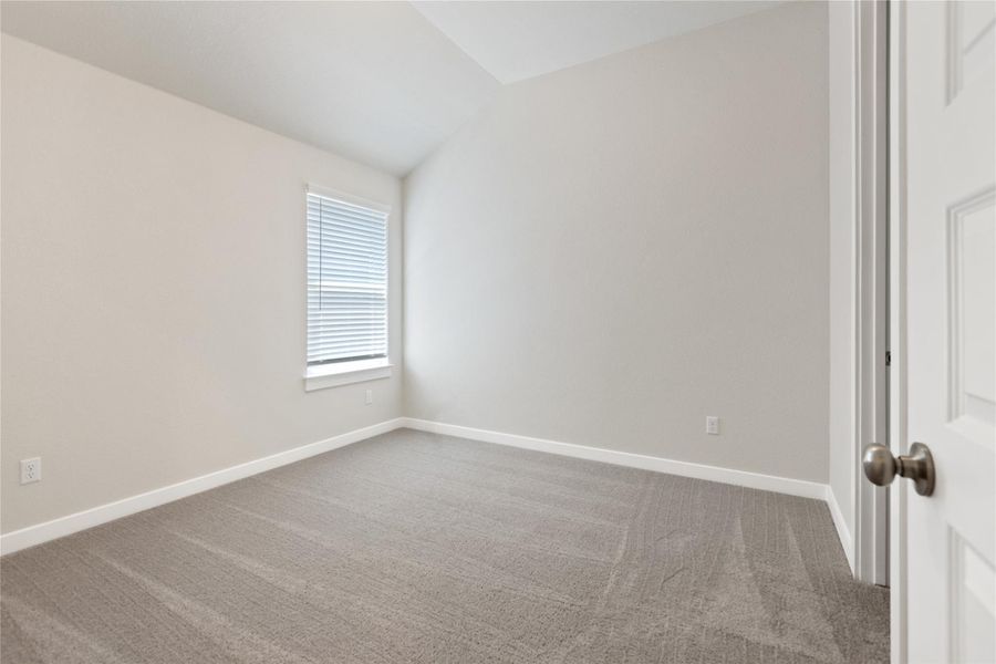 Spare room with vaulted ceiling and light carpet