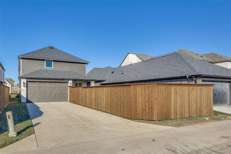 View of side of home with a shingled roof, a garage, and concrete driveway View of side of home with a shingled roof, a garage, and concrete driveway