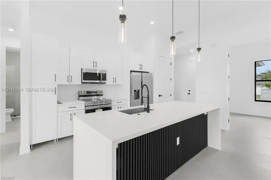 Kitchen featuring white cabinetry, quartz countertops, a black slatted-detail island with an undermount sink, matte black faucet, and three glass pendant lights