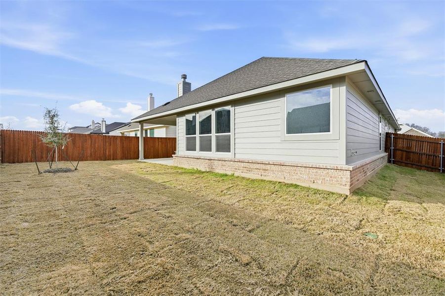 Rear view of property featuring a fenced backyard, a chimney, brick siding, a patio, and roof with shingles
