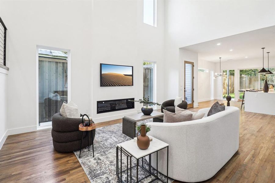 Living room with hardwood / wood-style flooring, a towering ceiling, and a chandelier