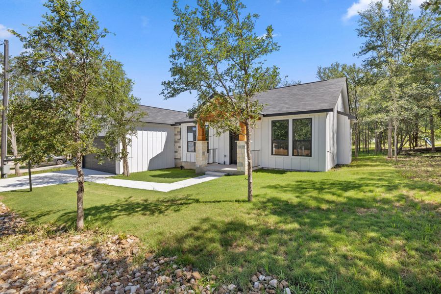 Modern dwelling with a stone-accented entry, nestled amidst natural landscaping and a verdant lawn. Modern dwelling with a stone-accented entry, nestled amidst natural landscaping and a verdant lawn.