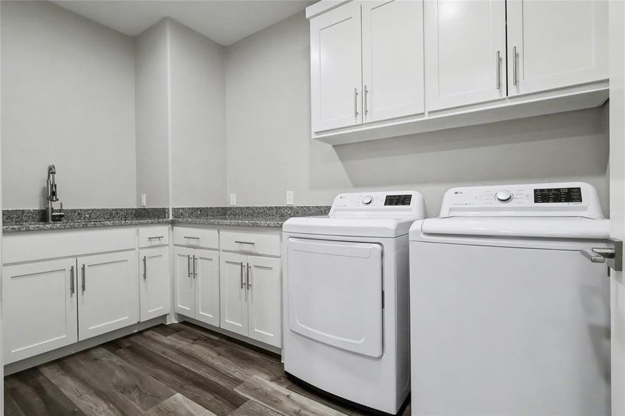 Utility room featuring white cabinetry, granite countertops, and wood-finish flooring
