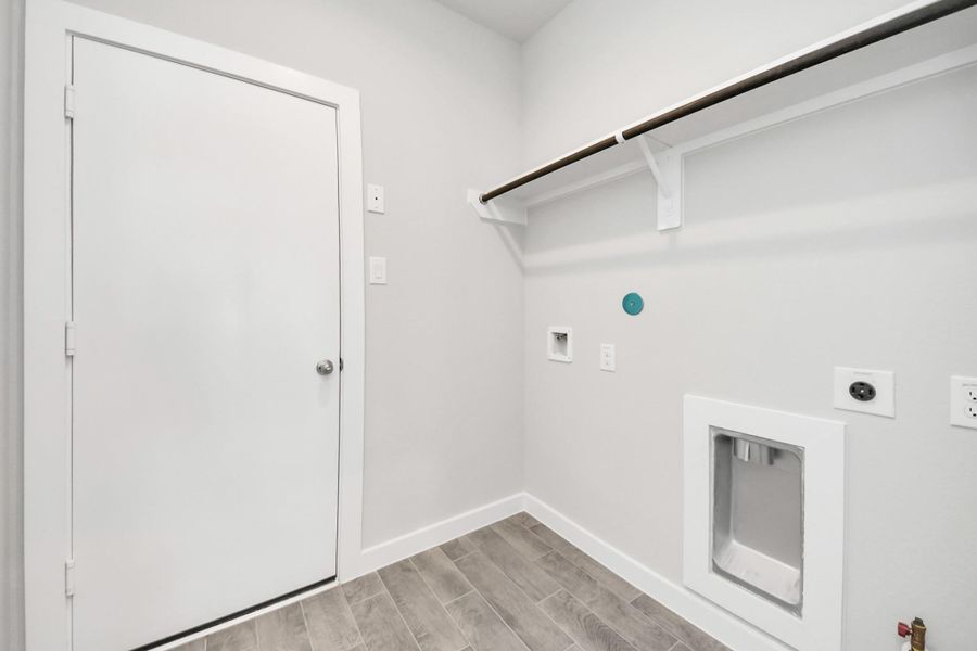 A perfect blend of functionality and comfort. Capture the essence of easy living with a first-floor laundry room, thoughtfully equipped with shelving for effortless organization. Both electric and gas connections available. Sample photo of completed home with similar floor plan. Actual colors and selections may vary.