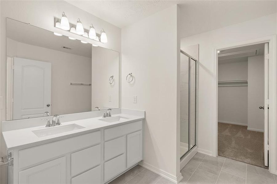 This primary bathroom is definitely move-in ready! Featuring a walk-in shower with tile surround, white stained cabinets with light countertops, spacious walk-in closet with shelving, high ceilings, custom paint, sleek and dark modern finishes.