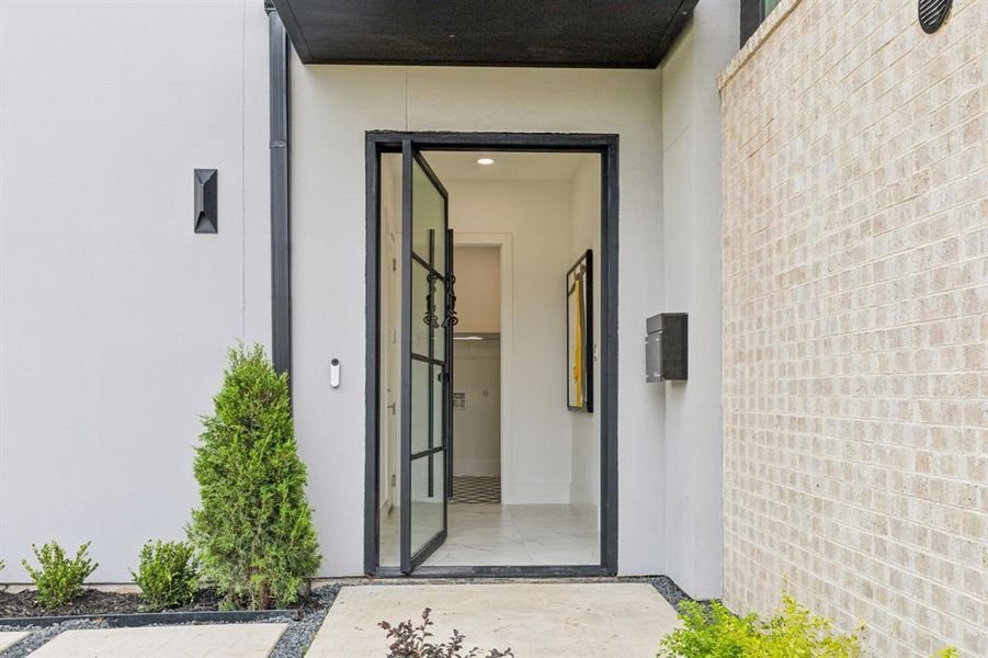 Sophisticated metal and glass pivot door greets you upon arrival.