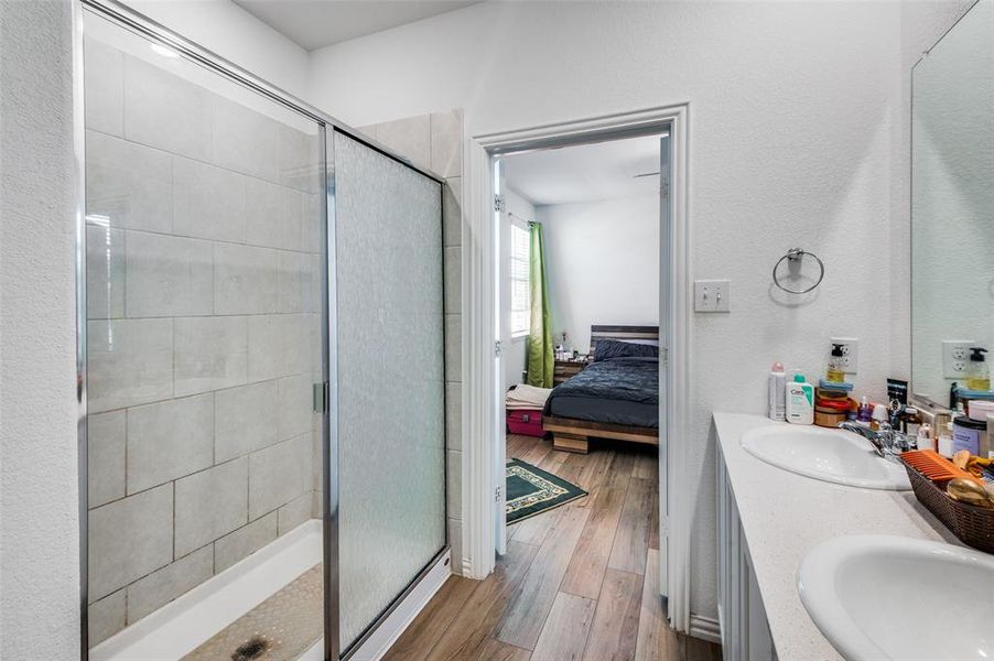 Bathroom with wood-type flooring, vanity, and a shower with shower door