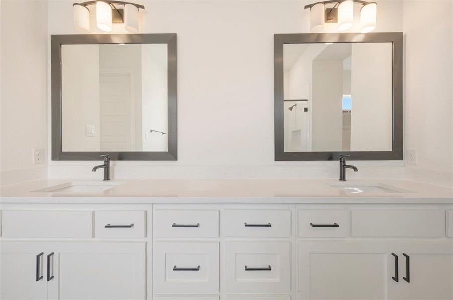 Dual vanities featuring white cabinetry with matte black hardware, integrated sinks, and light-toned countertops