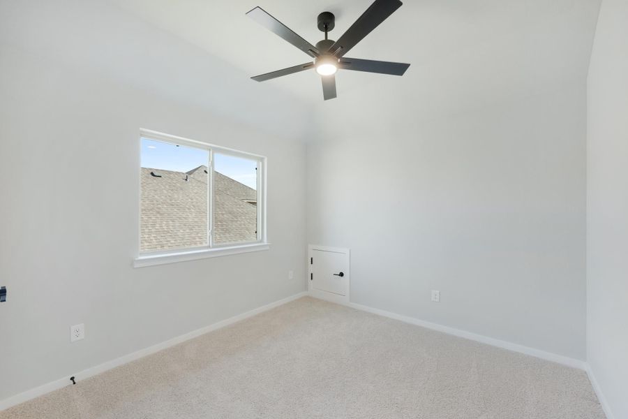 Empty bedroom with vaulted ceiling, black ceiling fan, carpet flooring, and a single window