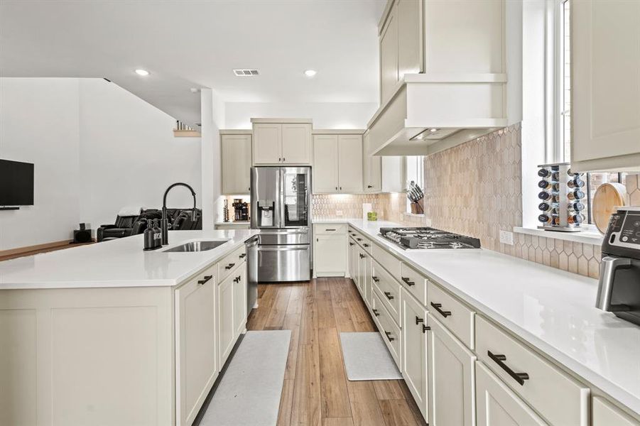 Kitchen with backsplash, appliances with stainless steel finishes, light wood-type flooring, light countertops, and recessed lighting