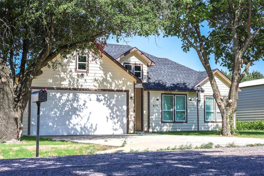 View of front facade featuring roof with shingles, a garage, and concrete driveway