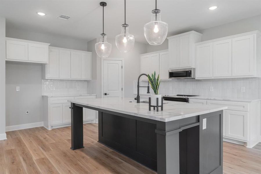 Kitchen with a kitchen island with sink, light hardwood / wood-style floors, and tasteful backsplash