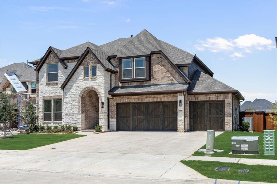 Two-story home with brick and stone exterior, three-car garage, and arched entryway