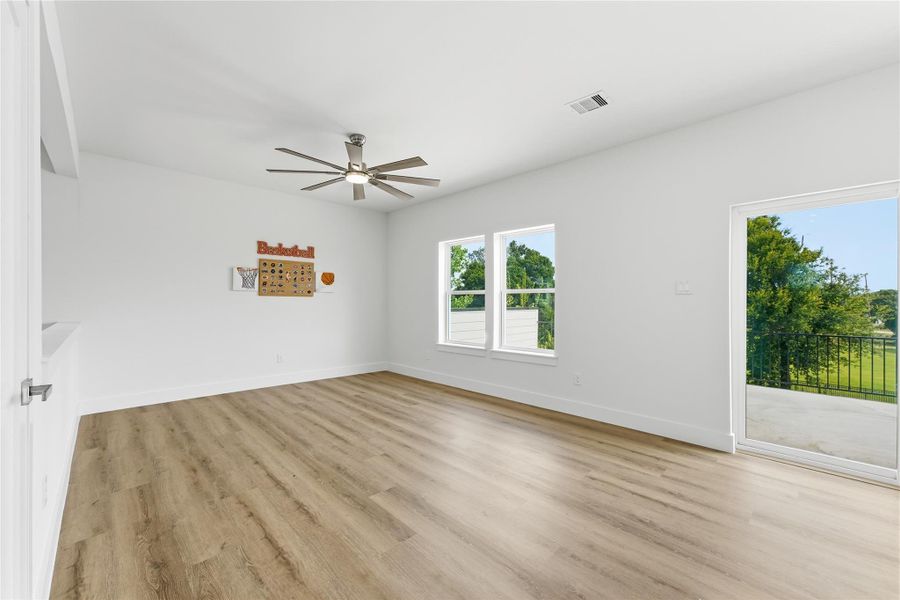 Open and airy game room with expansive windows, wood-look flooring, and direct access to an oversized balcony—ideal for gatherings and entertaining. Open and airy game room with expansive windows, wood-look flooring, and direct access to an oversized balcony—ideal for gatherings and entertaining.