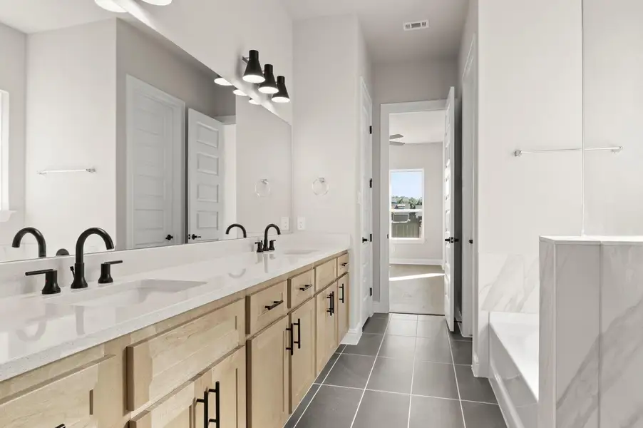 Full bathroom with double vanity, a bath, and dark tile patterned flooring Full bathroom with double vanity, a bath, and dark tile patterned flooring