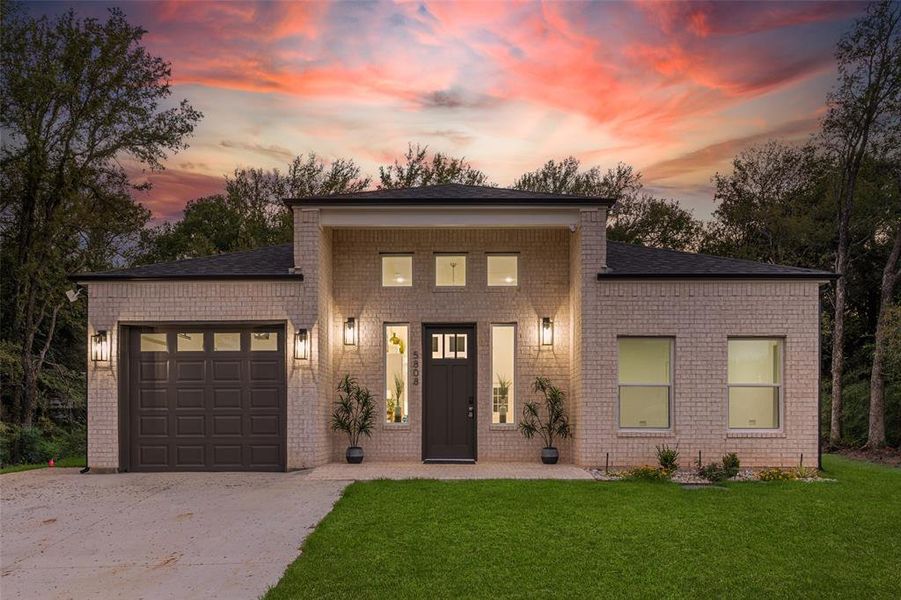 View of front of home featuring a garage and a yard