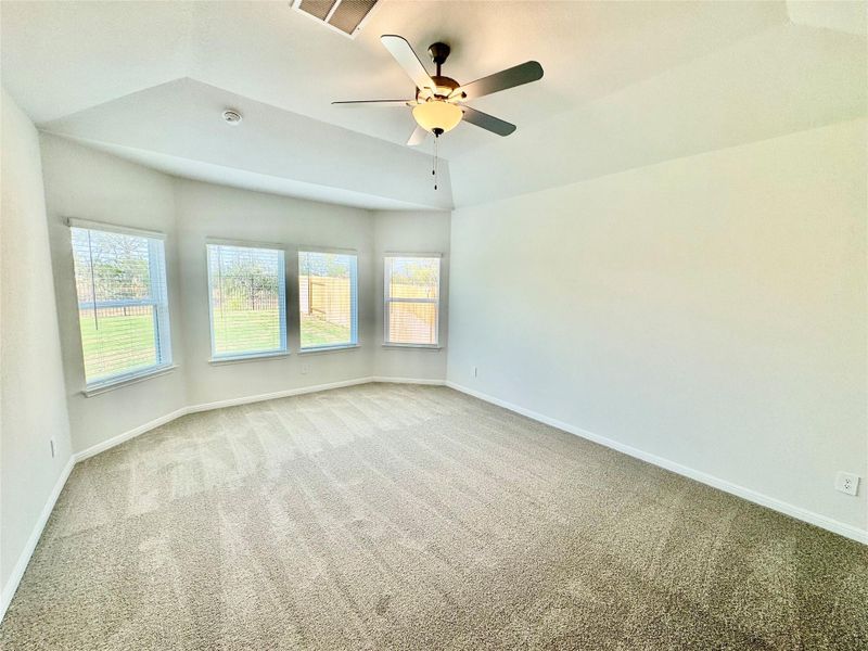 Carpeted empty room with a ceiling fan and lofted ceiling