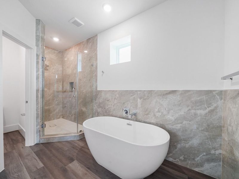 Experience luxury and relaxation in this modern bathroom oasis, featuring a sleek freestanding tub and elegant glass-enclosed shower, representative of the high-quality finishes in our vibrant community.Photo Disclaimer: Photos are representative of the community and may depict a similar floor plan, model home, or previously completed residence.
