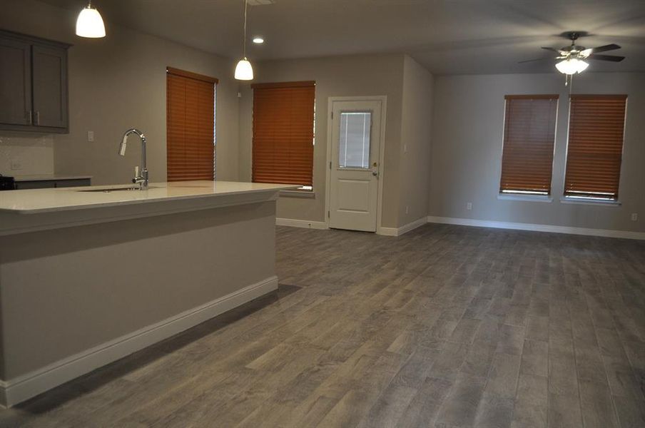 Kitchen with ceiling fan, dark hardwood / wood-style flooring, sink, and hanging light fixtures