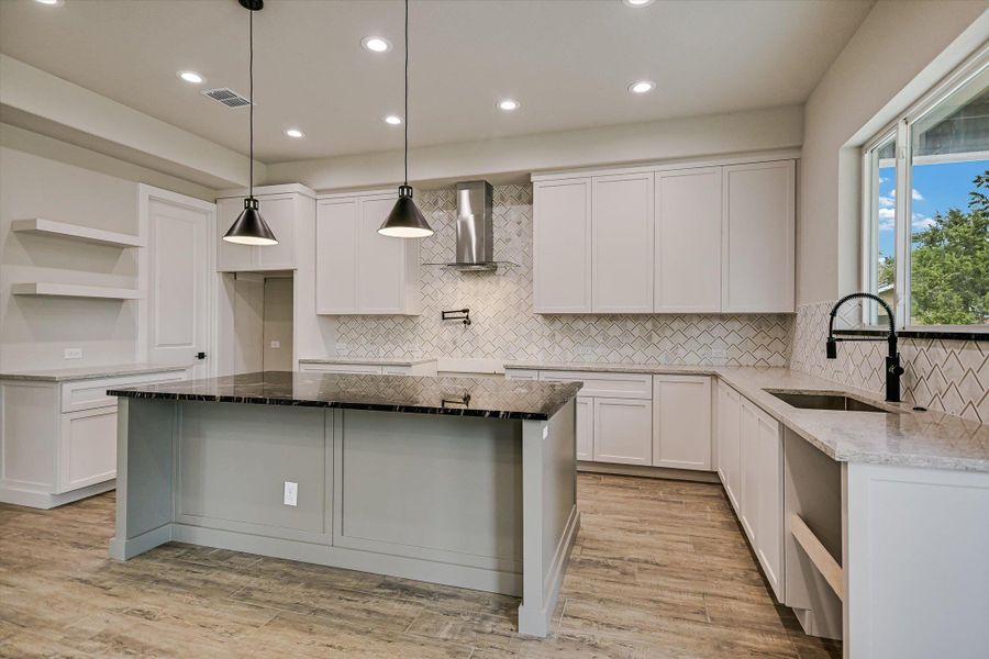 Kitchen featuring dark stone counters, open shelves, and light wood-style floors