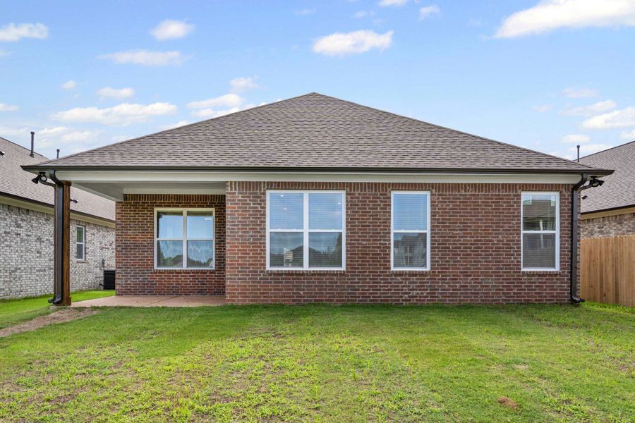 Red brick exterior with multiple windows, a covered patio area with a wood-wrapped column, and a spacious green lawn Red brick exterior with multiple windows, a covered patio area with a wood-wrapped column, and a spacious green lawn
