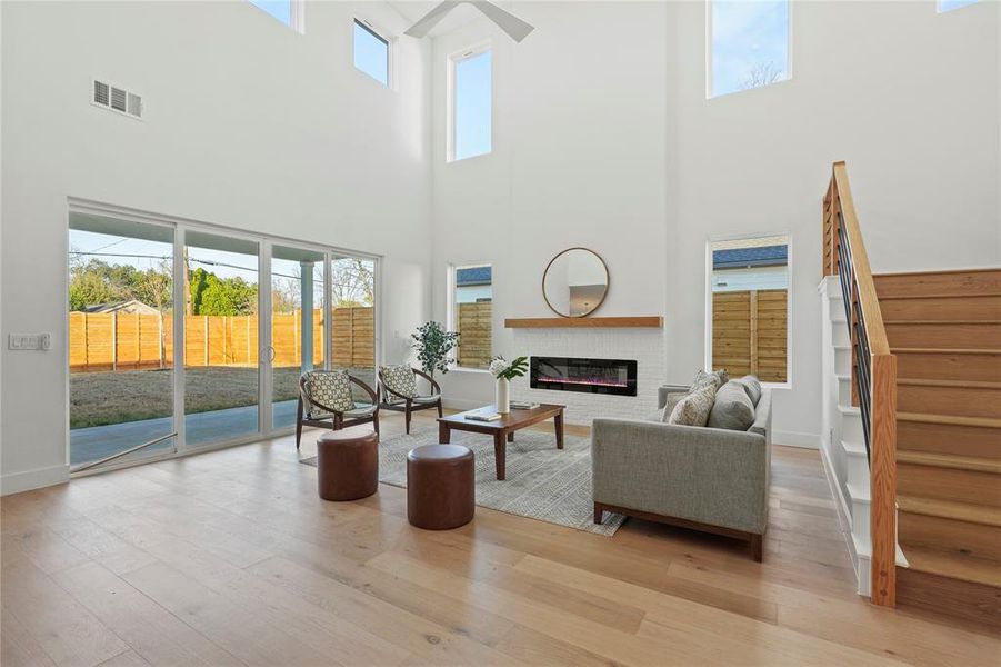 Living room with a glass covered fireplace, plenty of natural light, stairway, and a towering ceiling