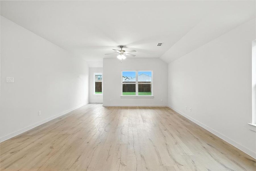 Unfurnished room featuring a ceiling fan, light wood-style floors, and lofted ceiling