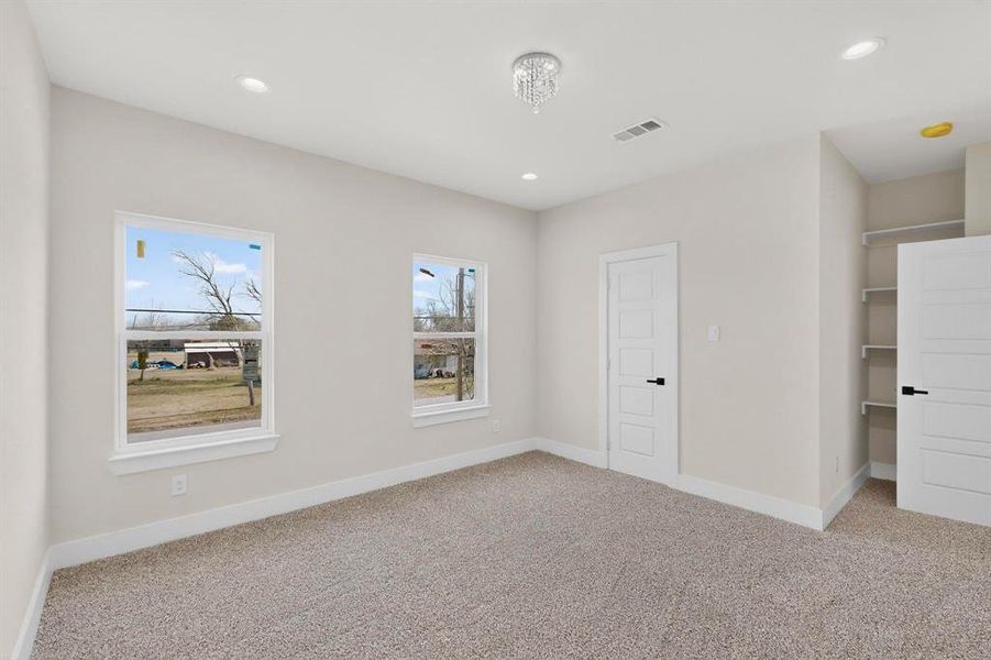 Bedroom with light carpet, a spacious closet, and recessed lighting Bedroom with light carpet, a spacious closet, and recessed lighting