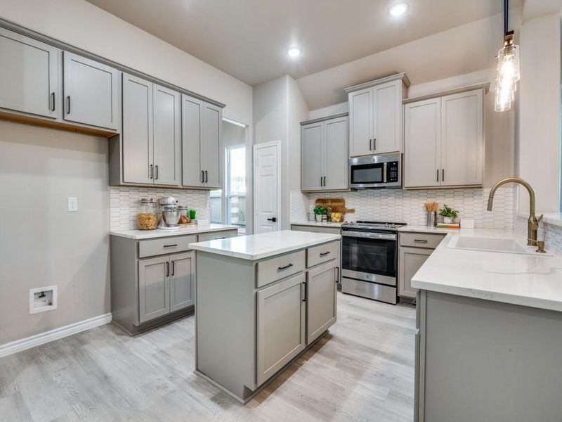 Kitchen with a sink, appliances with stainless steel finishes, light wood-style floors, gray cabinets, and decorative backsplash Kitchen with a sink, appliances with stainless steel finishes, light wood-style floors, gray cabinets, and decorative backsplash