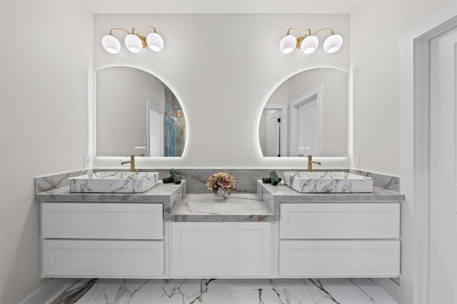 Elegant stone countertops and dual vessel sinks define this contemporary vanity space.