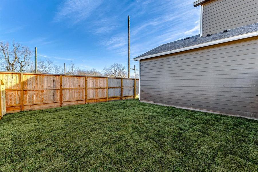 The contemporary exterior design extends to this side view, showcasing clean lines, durable siding, and bright windows. The expansive yard offers endless possibilities for landscaping or outdoor activities.