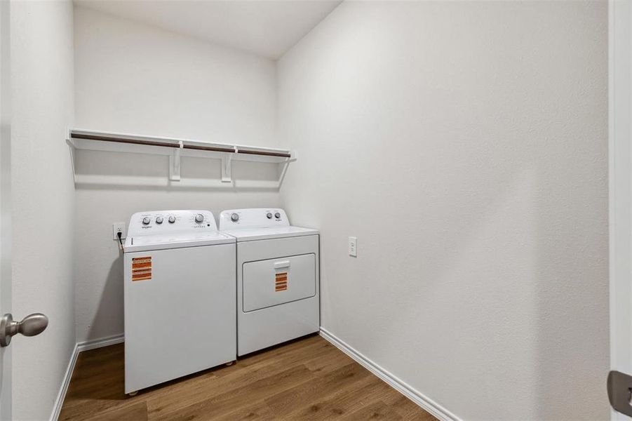 Dedicated laundry area featuring wood-finish flooring, overhead shelving, and a neutral color palette