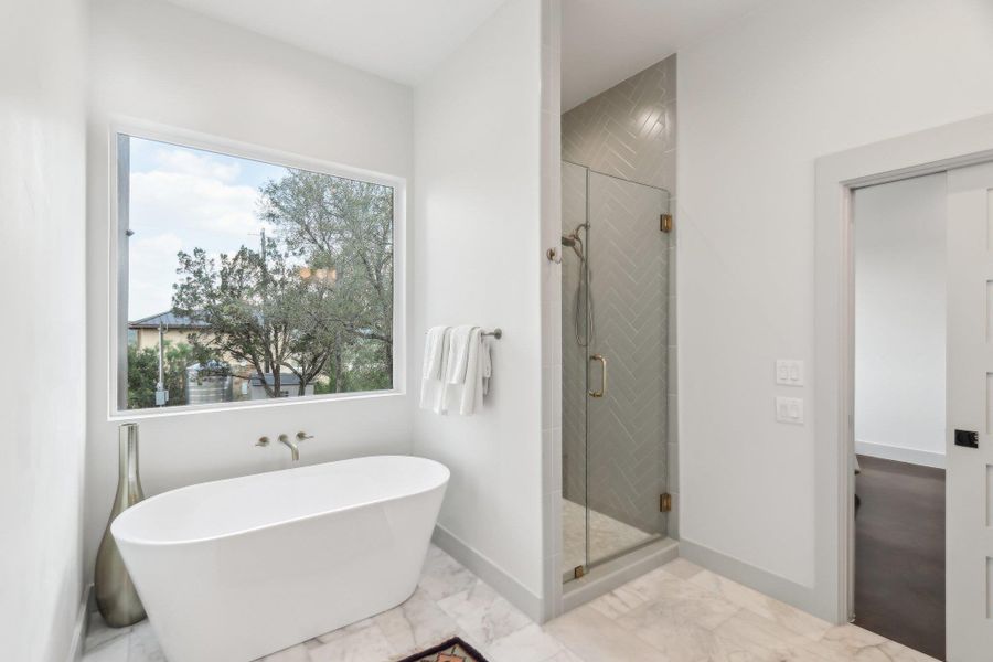 Bathroom featuring marble finish flooring, a freestanding bath, plenty of natural light, and a stall shower Bathroom featuring marble finish flooring, a freestanding bath, plenty of natural light, and a stall shower