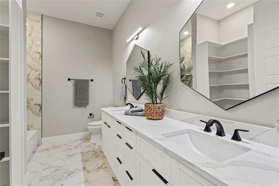 Full bath featuring double vanity, marble finish flooring, a spacious closet, and recessed lighting