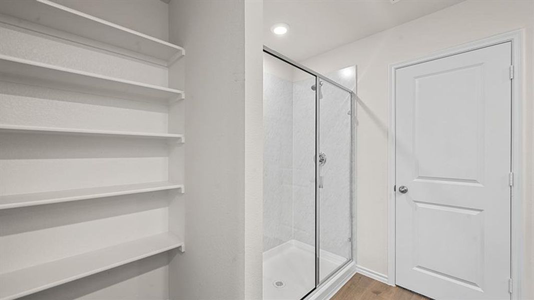 Bathroom with a shower stall, light wood finished floors, and recessed lighting