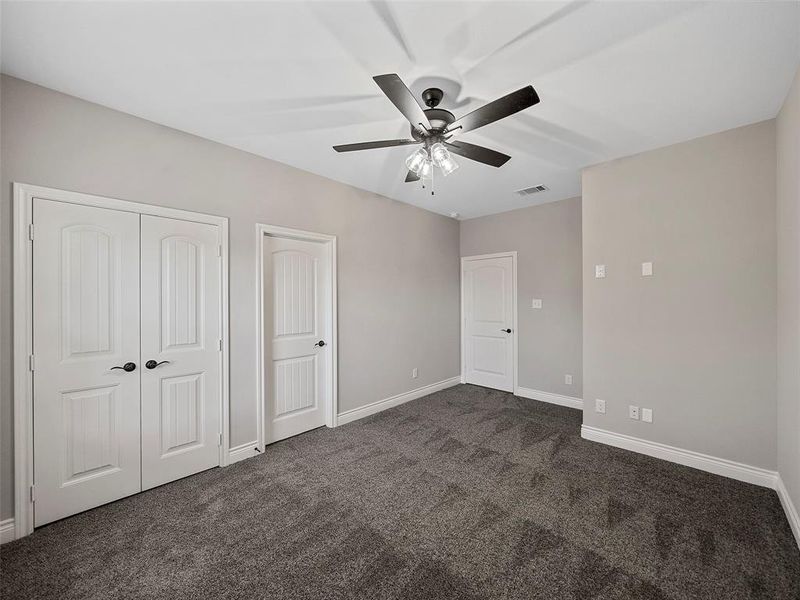 Unfurnished bedroom with dark carpet, a closet, and ceiling fan Unfurnished bedroom with dark carpet, a closet, and ceiling fan