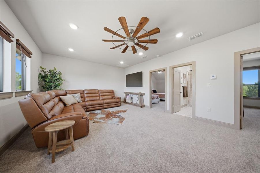 Spacious carpeted room featuring a unique wooden ceiling fan, recessed lighting, and multiple window openings