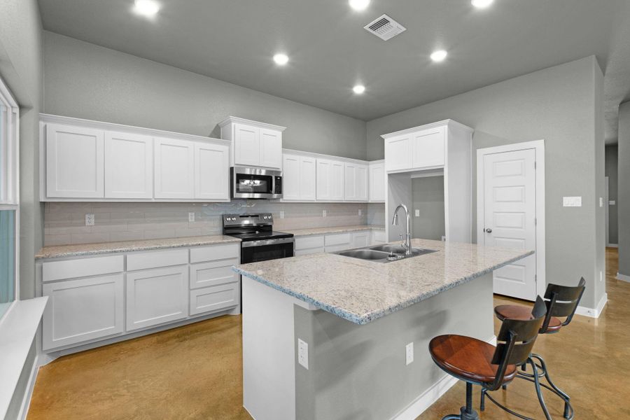 A well-lit kitchen with granite counters and abundant cabinet storage.