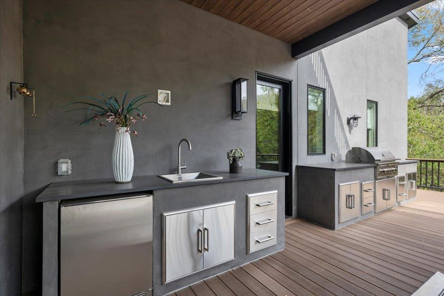 The outdoor kitchen features a Coyote LS-Series 36 inch 5burner gas grill, a Zephyr outdoor beverage cooler & a Ruvati insulated ice chest sink.