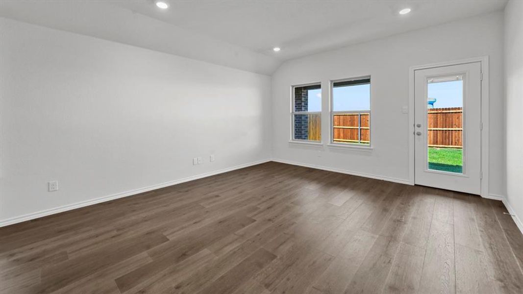 Spacious room featuring wood-finish flooring, recessed lighting, and white baseboards