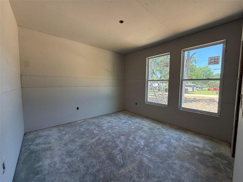 Room featuring two windows providing natural light, unfinished drywall, and a concrete subfloor