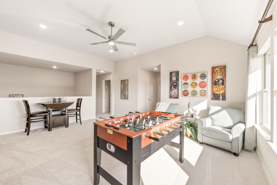 Game room with foosball table, seating area, ceiling fan, and dining nook on carpet flooring Game room with foosball table, seating area, ceiling fan, and dining nook on carpet flooring