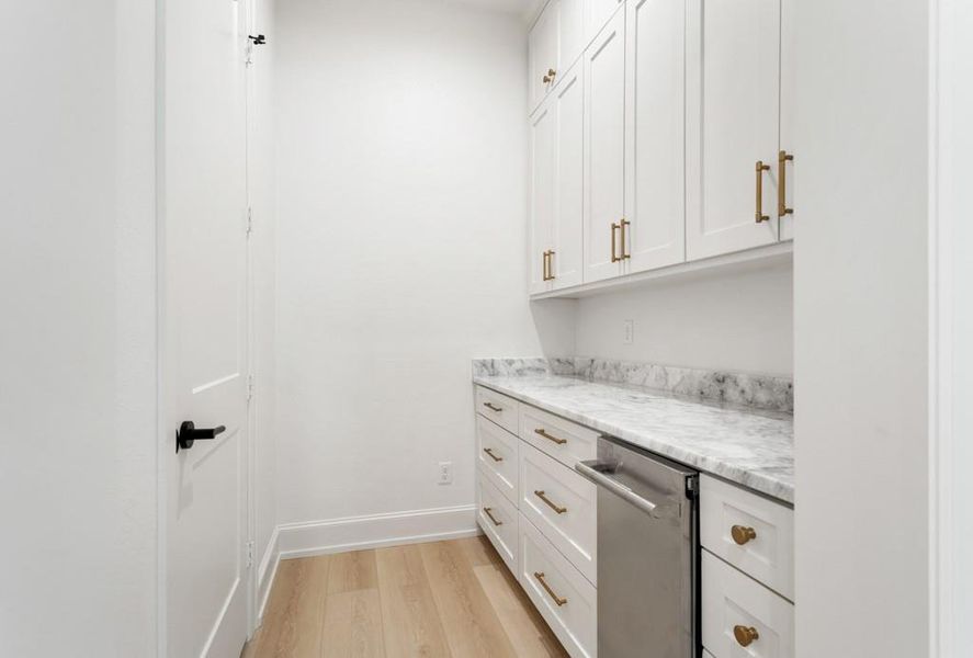Bar with white cabinets, light wood finished floors, stainless steel dishwasher, and light stone counters