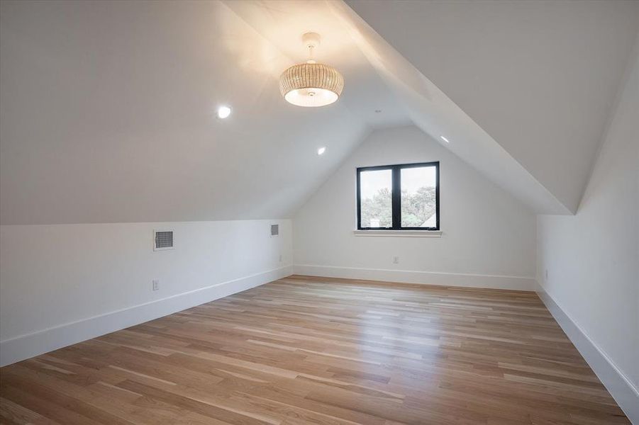 Bonus room with lofted ceiling and light hardwood / wood-style flooring