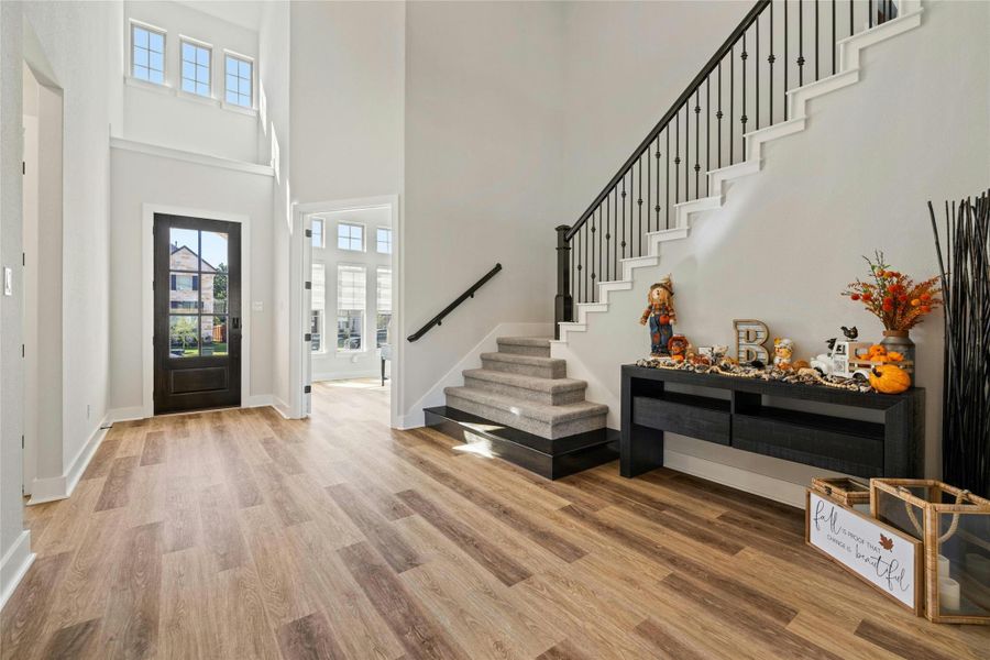 Foyer entrance featuring a towering ceiling, stairs, wood finished floors, and plenty of natural light Foyer entrance featuring a towering ceiling, stairs, wood finished floors, and plenty of natural light