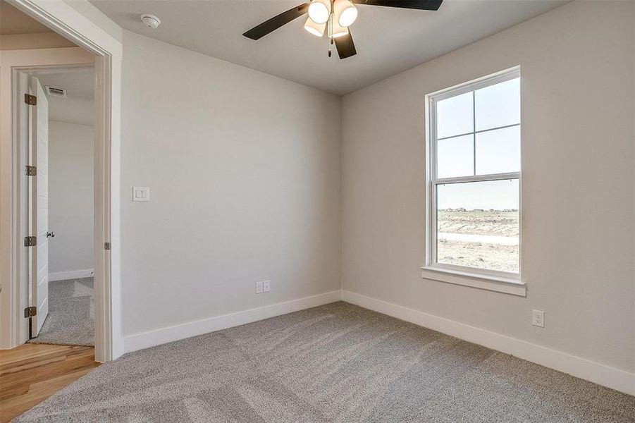 Carpeted empty room featuring ceiling fan