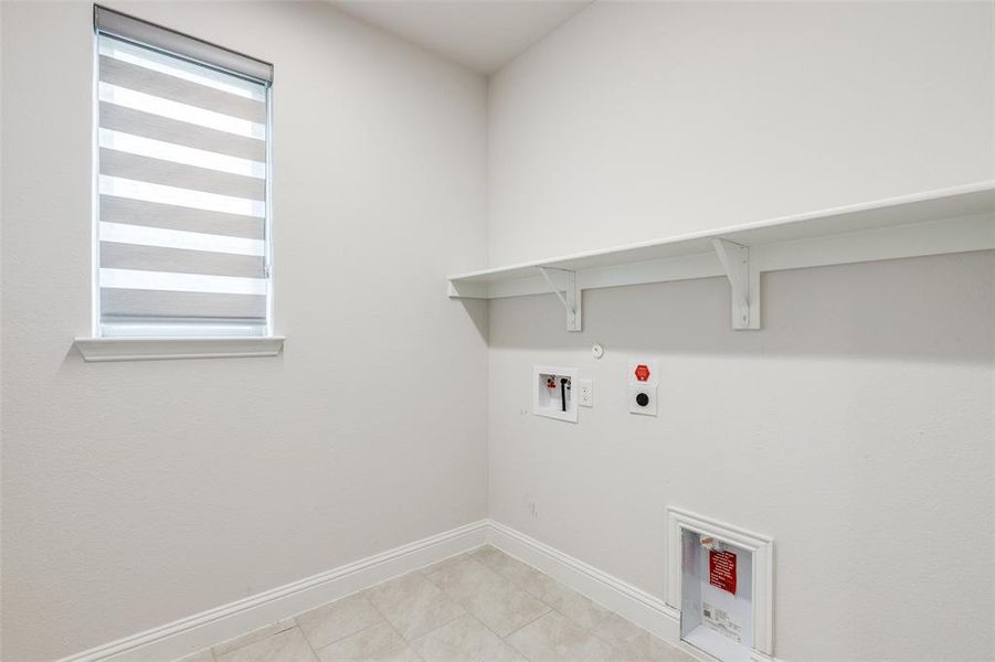 Washroom with hookup for a gas dryer, electric dryer hookup, baseboards, hookup for a washing machine, and light tile patterned floors